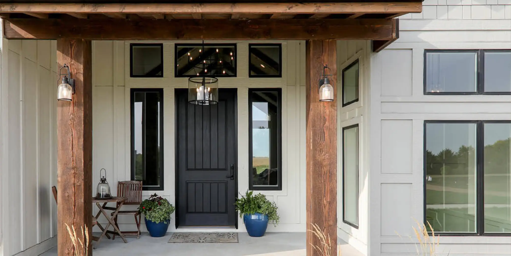 Black exterior door with modern design, surrounded by decorative plants and outdoor lighting, showcasing a stylish entryway for home improvement and energy efficiency.